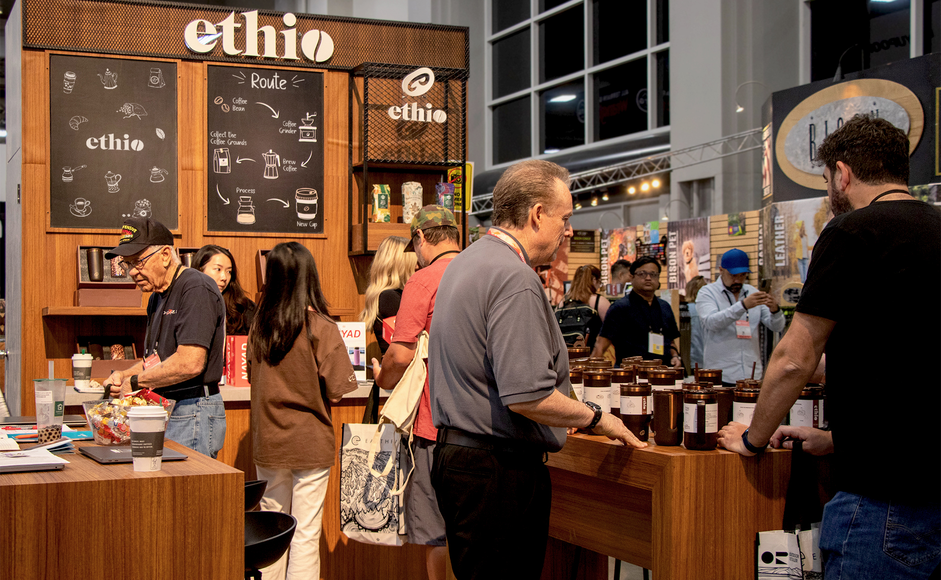 Ethio coffee booth at a trade show, featuring branded signage, wooden displays, and visitors browsing mugs and products.