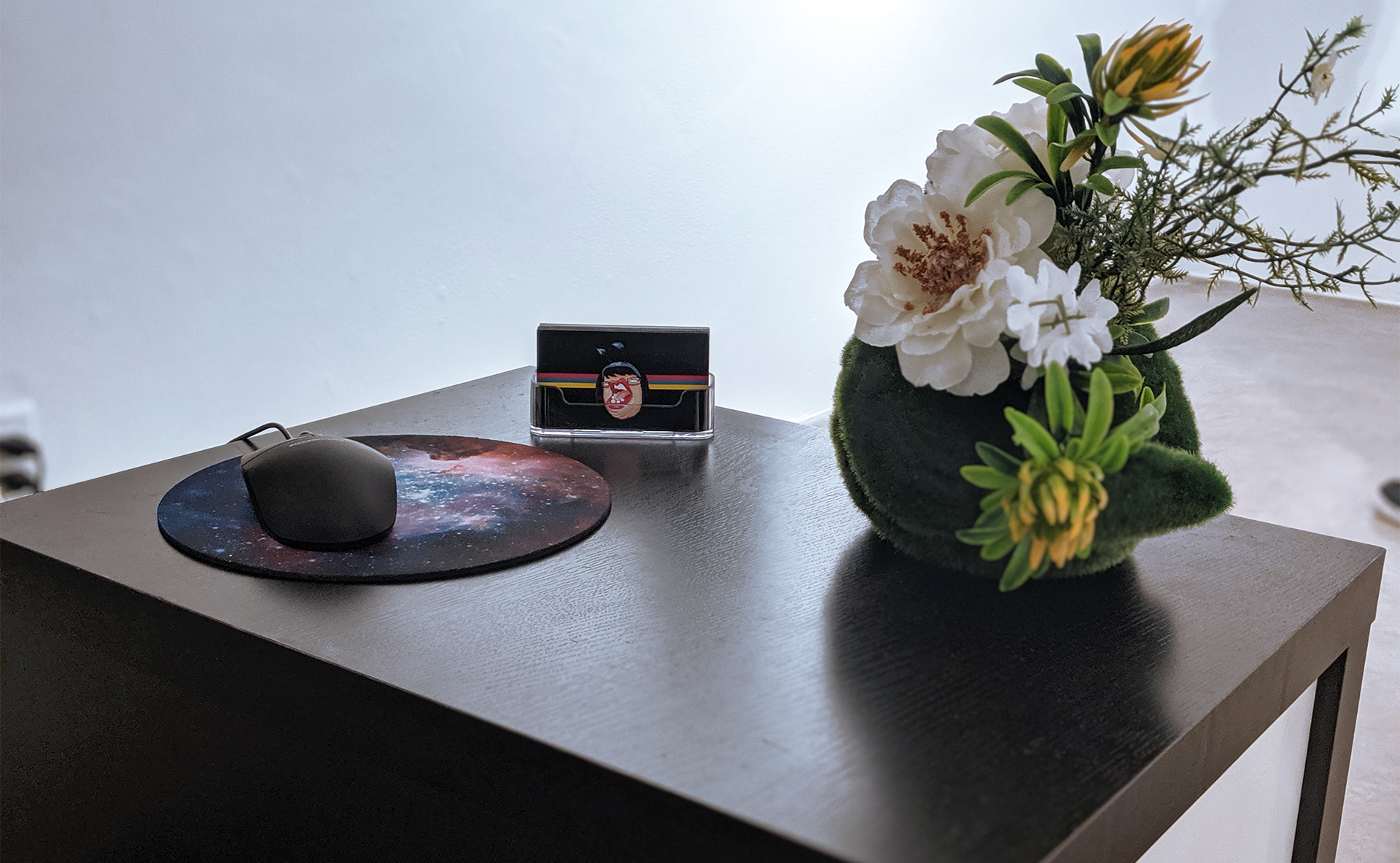 Gallery installation detail showing mouse, interface controls, and decorative elements on display table.