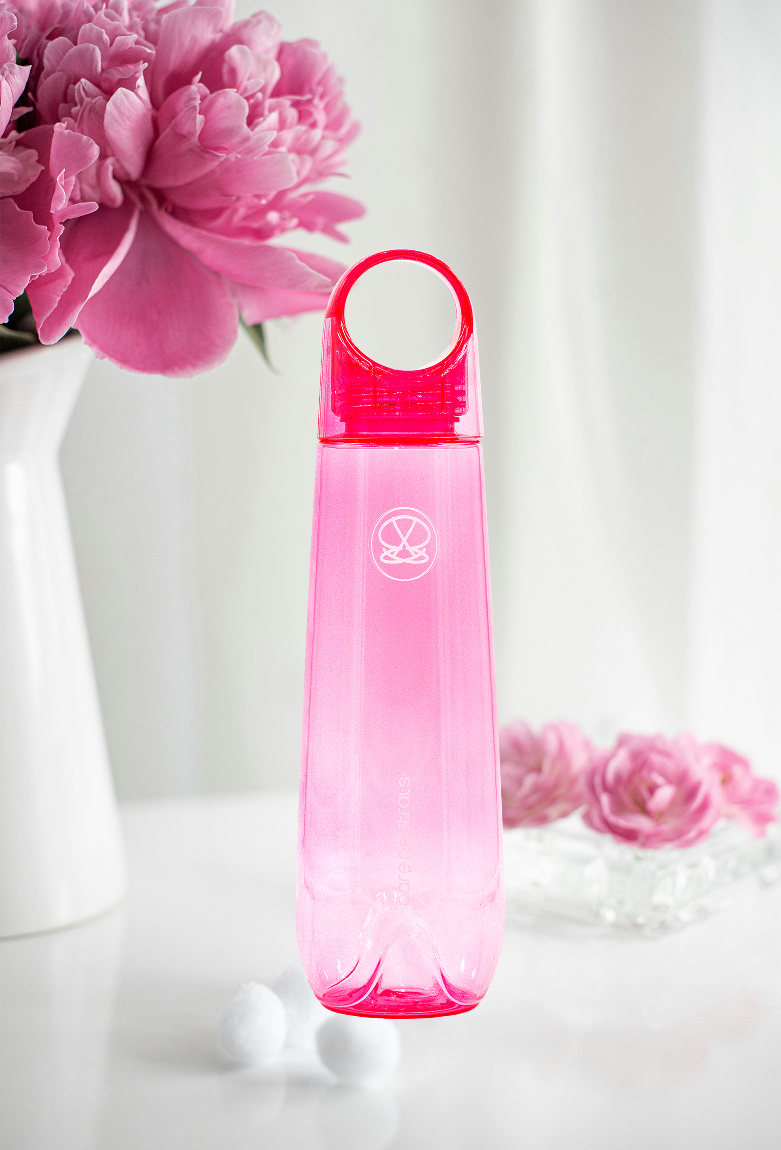 The before image of a pink water bottle with flowers in the background.